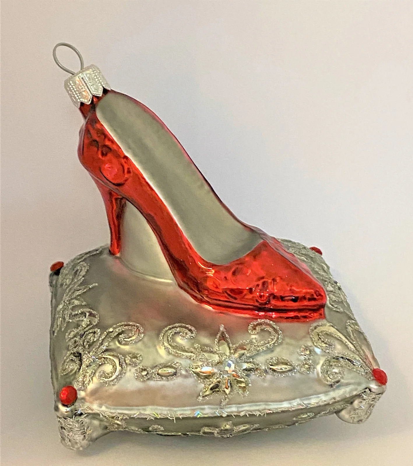 GMC Roter High Heels auf silbernem Brokatkissen