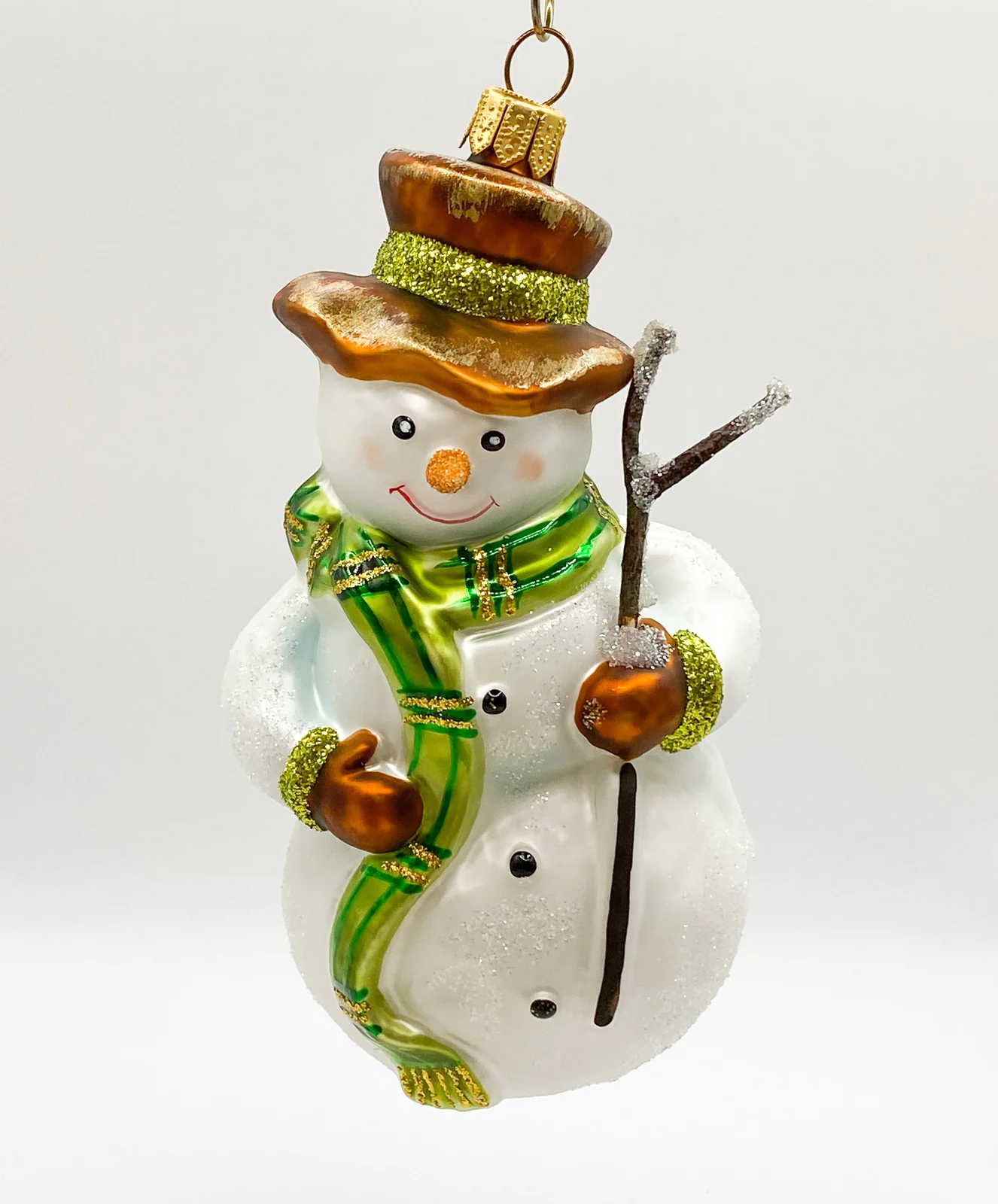 Hanco Schneemann mit grünem Schal und Reisig-Stecken