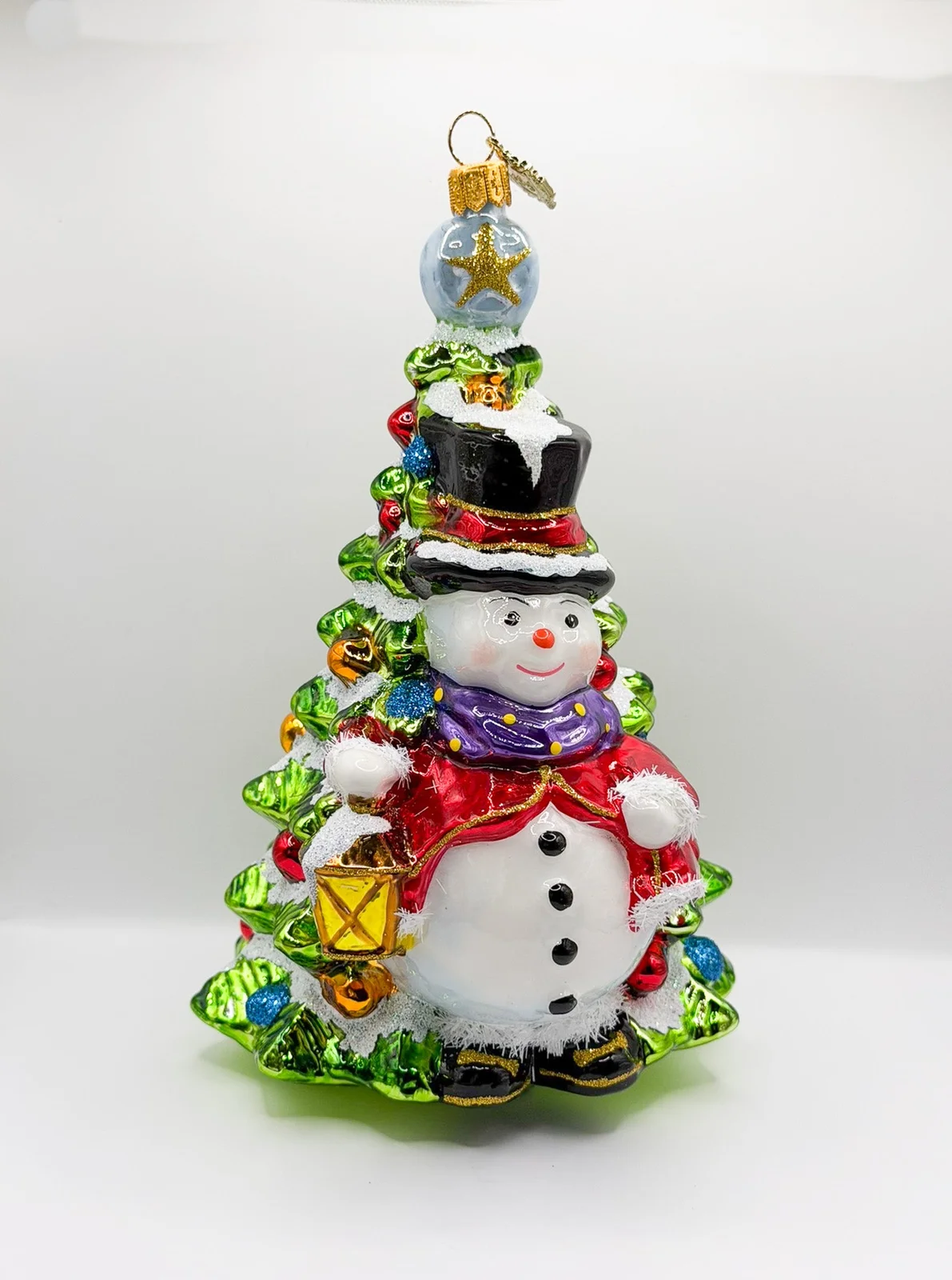 Glassware Schneemann mit Laterne steht vor dem Weihnachtsbaum