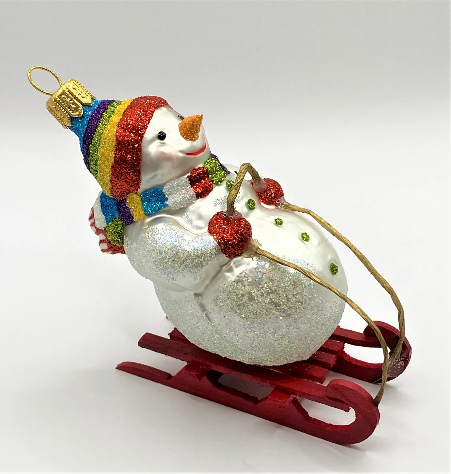 Hanco Schneemann mit bunter Mütze auf Schlitten