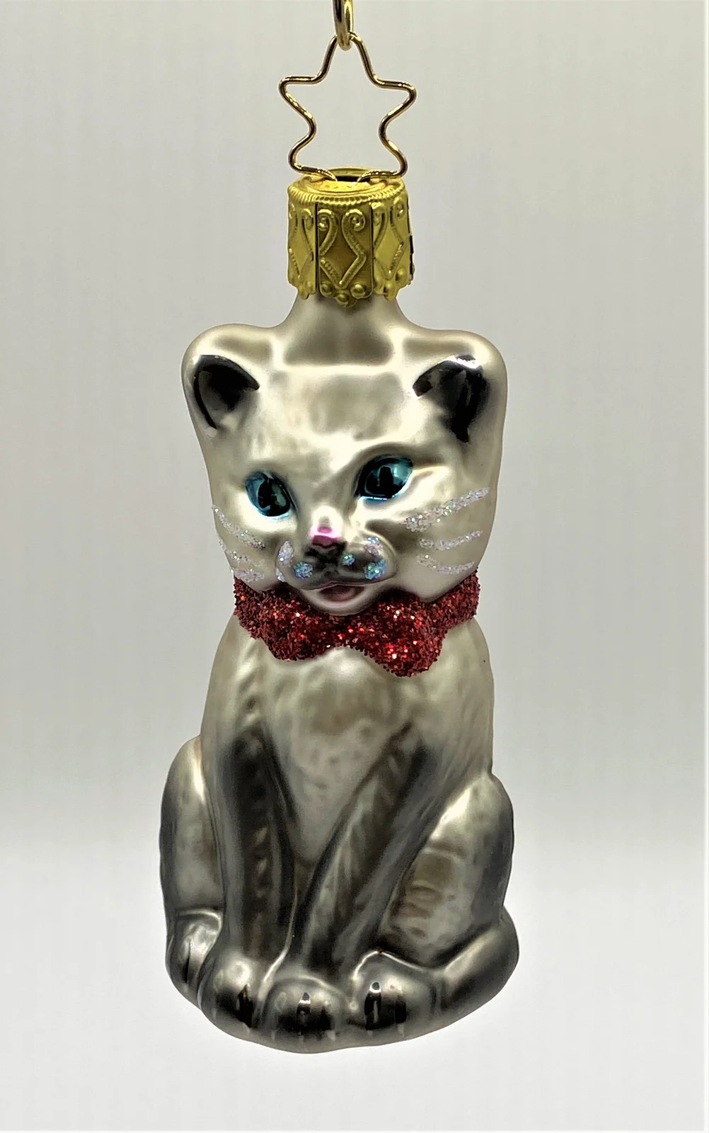 Inge-Glas Sitzende graue Katze mit blauen Augen und roter Schleife