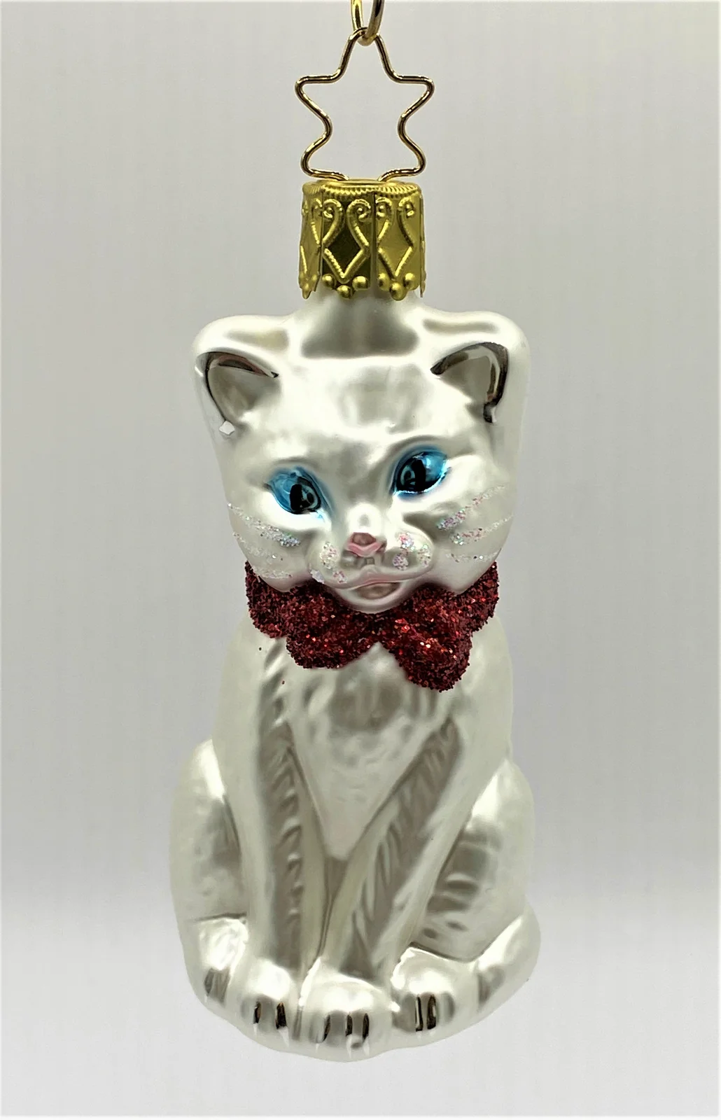 Inge-Glas Sitzende weisse Katze mit blauen Augen und roter Schleife