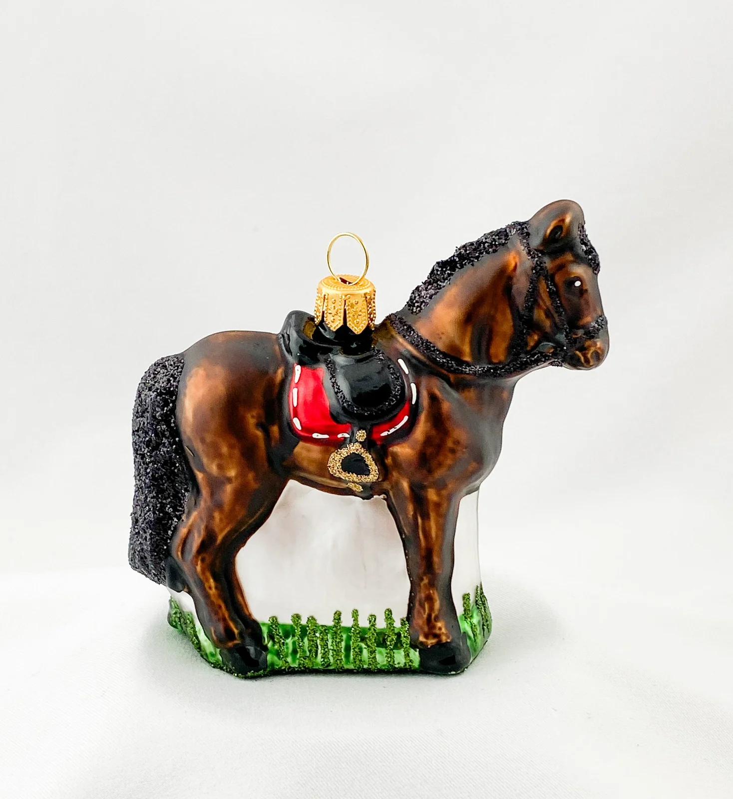 Glaspol Dunkelbraunes Pferd mit roter Satteldecke