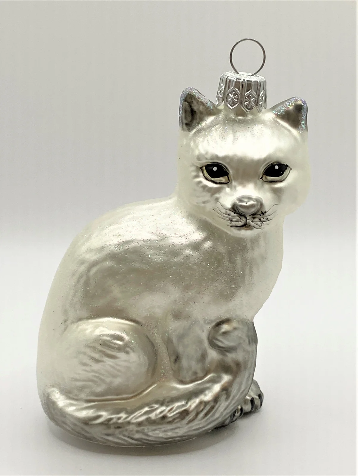 Glaspol Sitzende weisse Katze mit grauem Schwanz