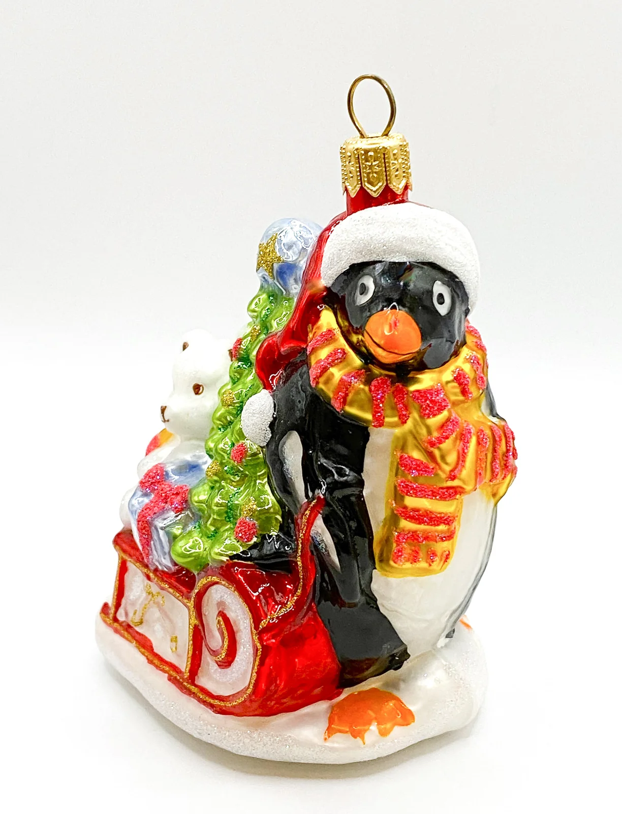 Glassware Pinguin bringt den Weihnachtsbaum und Geschenke auf dem Schlitten
