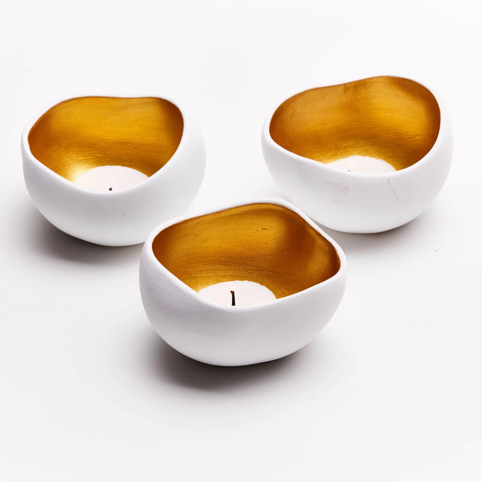 Anoq Set aus 3 weißen und goldfarbenen Keramik-Teelichthaltern in unregelmäßiger Form